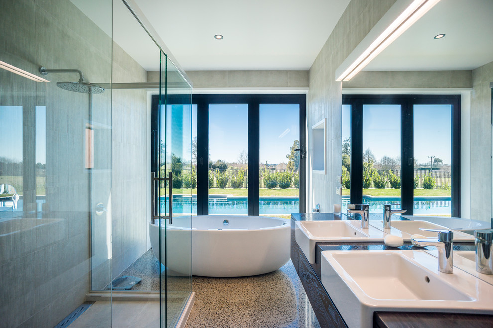 На фото: ванная комната среднего размера в современном стиле с открытыми фасадами, отдельно стоящей ванной, угловым душем, бетонным полом и столешницей из ламината