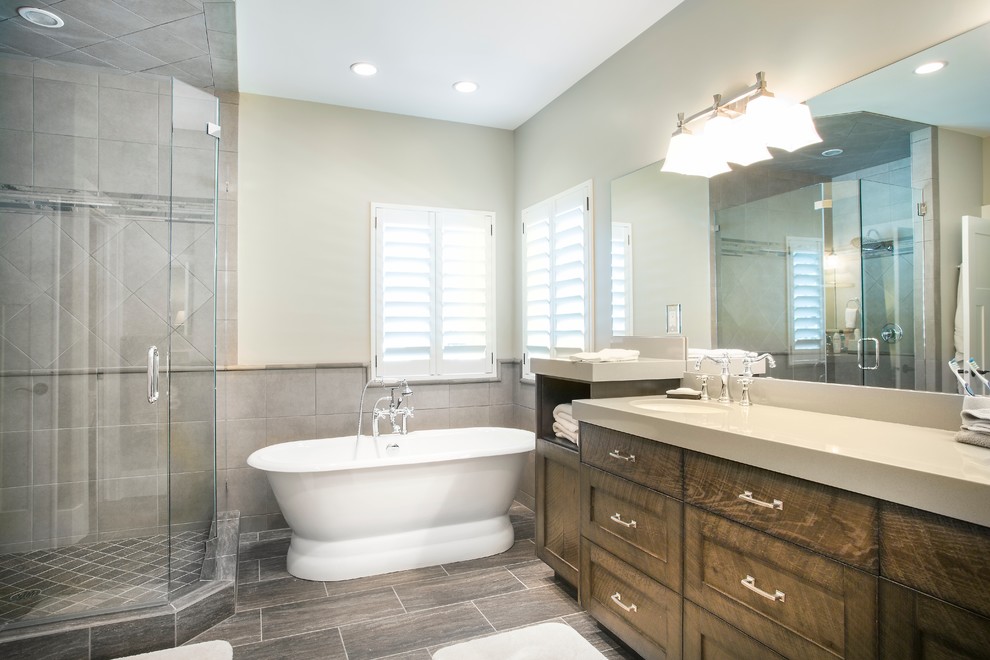Inspiration for a medium sized traditional ensuite bathroom in Salt Lake City with recessed-panel cabinets, dark wood cabinets, a freestanding bath, a corner shower, beige tiles, ceramic tiles, beige walls, porcelain flooring, a submerged sink, engineered stone worktops, brown floors, a hinged door and beige worktops.