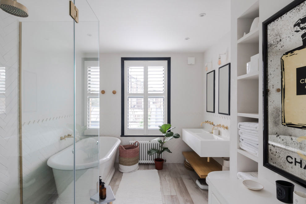 Inspiration for a scandinavian bathroom in London with a freestanding bath, white walls, light hardwood flooring, an integrated sink, beige floors, white worktops, double sinks and a floating vanity unit.