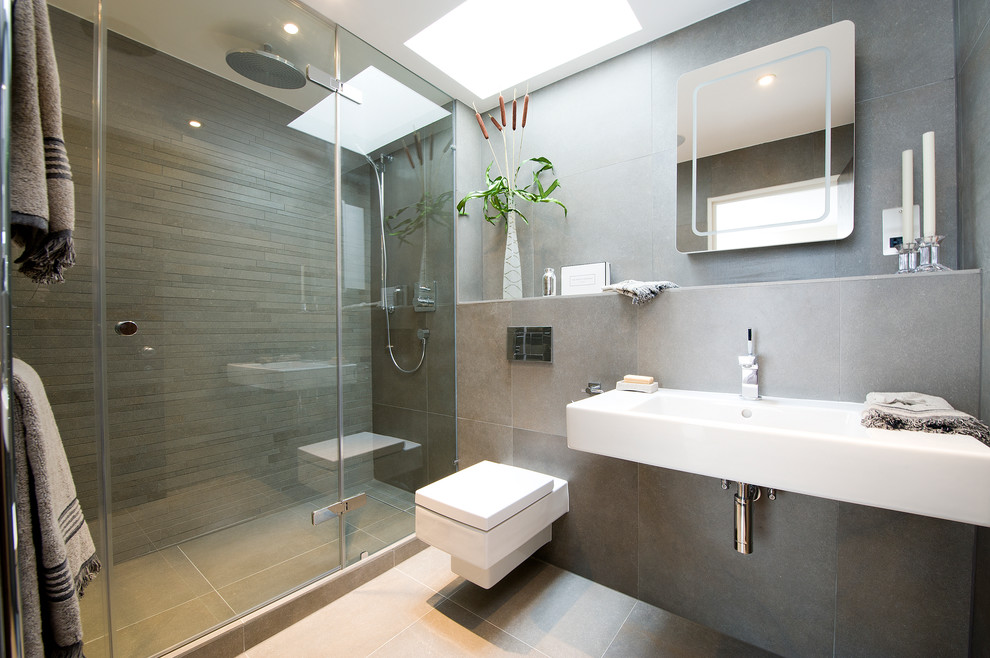 Idéer för ett mellanstort modernt en-suite badrum, med ett väggmonterat handfat, en vägghängd toalettstol, grå kakel, keramikplattor, grå väggar, klinkergolv i keramik och en dusch i en alkov