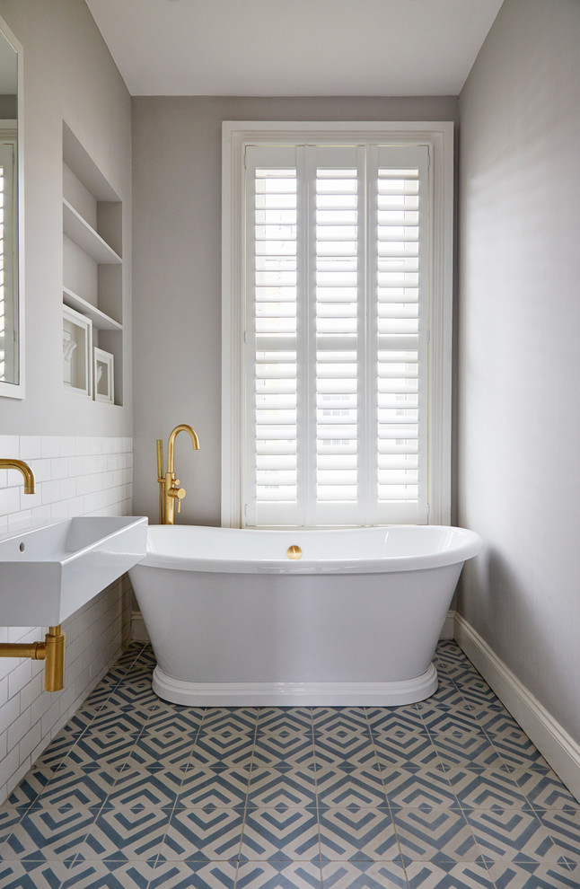 Пример оригинального дизайна: ванная комната в скандинавском стиле с открытыми фасадами, отдельно стоящей ванной, белой плиткой, плиткой кабанчик, серыми стенами, полом из цементной плитки, монолитной раковиной и синим полом
