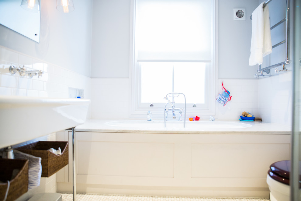 Klassisk inredning av ett litet badrum för barn, med ett platsbyggt badkar, en toalettstol med separat cisternkåpa, vit kakel, grå väggar, mosaikgolv, ett avlångt handfat, vitt golv, en hörndusch, dusch med gångjärnsdörr och keramikplattor
