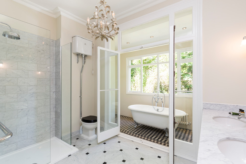 Immagine di una stanza da bagno vittoriana con vasca con piedi a zampa di leone, WC a due pezzi, piastrelle grigie, piastrelle bianche, pareti beige, lavabo sottopiano e doccia aperta