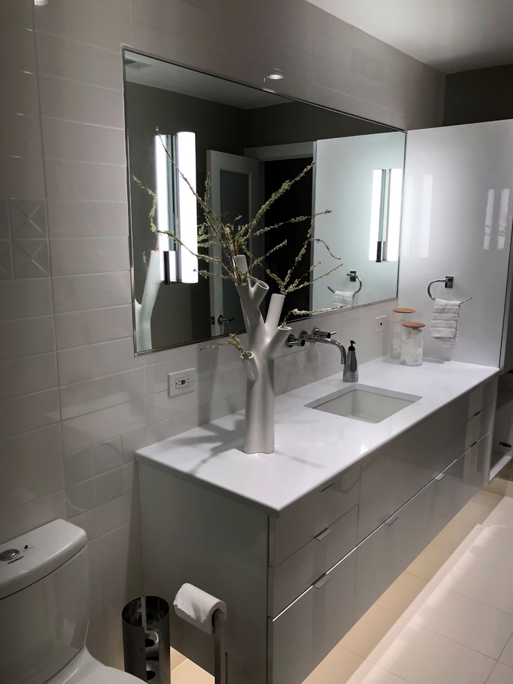 Small minimalist master white tile and ceramic tile porcelain tile and white floor bathroom photo in Dallas with glass-front cabinets, gray cabinets, a one-piece toilet, gray walls, an undermount sink, quartz countertops and white countertops