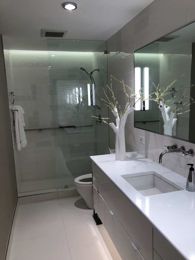 Exempel på ett litet modernt vit vitt en-suite badrum, med luckor med glaspanel, grå skåp, en öppen dusch, en toalettstol med hel cisternkåpa, vit kakel, keramikplattor, grå väggar, klinkergolv i porslin, ett undermonterad handfat, bänkskiva i kvarts, vitt golv och med dusch som är öppen