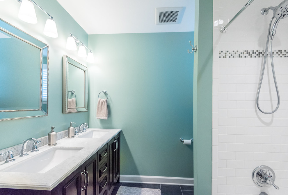 Inspiration pour une salle de bain principale avec des carreaux de céramique, un placard avec porte à panneau surélevé, des portes de placard marrons, une baignoire posée, un combiné douche/baignoire, WC à poser, un carrelage blanc, un mur vert, un sol en ardoise, un lavabo encastré, un plan de toilette en marbre, un sol gris et une cabine de douche avec un rideau.