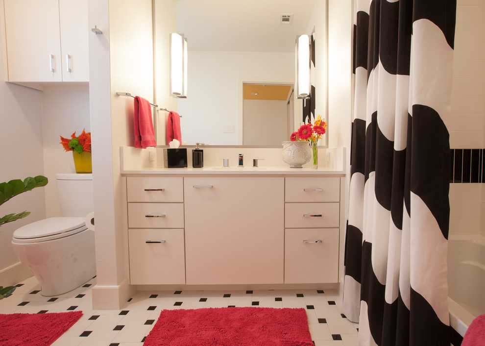 На фото: ванная комната в современном стиле с врезной раковиной, плоскими фасадами, белыми фасадами, столешницей из искусственного кварца, ванной в нише, душем над ванной, раздельным унитазом, разноцветной плиткой и керамогранитной плиткой с