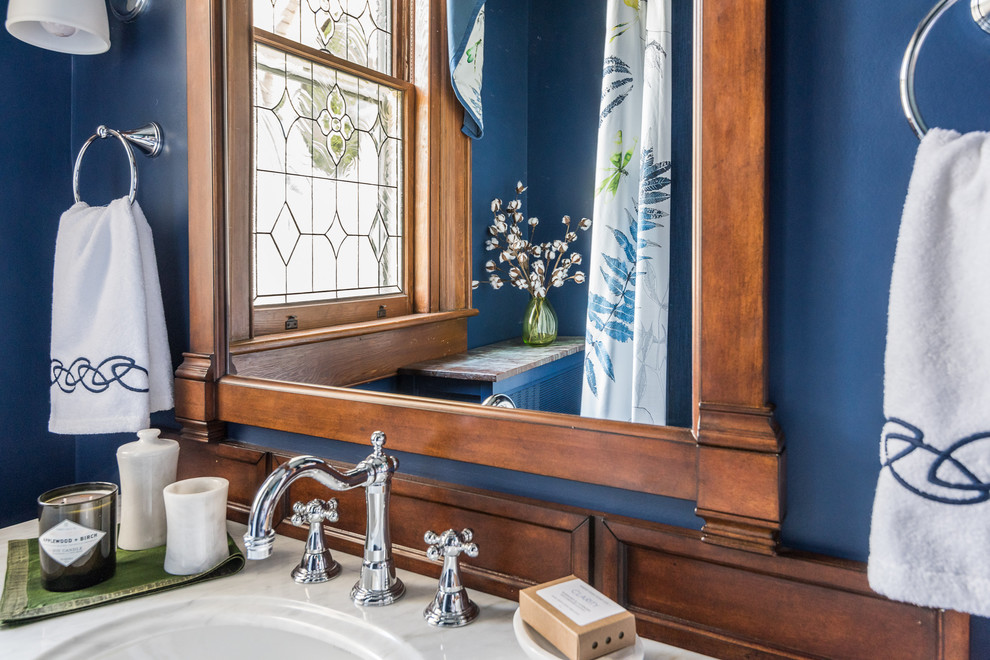 Inredning av ett klassiskt litet badrum, med skåp i mörkt trä, ett badkar med tassar, en dusch/badkar-kombination, blå väggar, cementgolv, ett undermonterad handfat, flerfärgat golv och dusch med duschdraperi