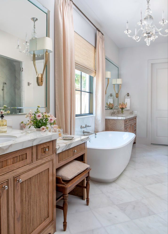 Freestanding bathtub - mid-sized transitional master marble floor and white floor freestanding bathtub idea in Houston with medium tone wood cabinets, an undermount sink, marble countertops, white countertops, white walls and beaded inset cabinets