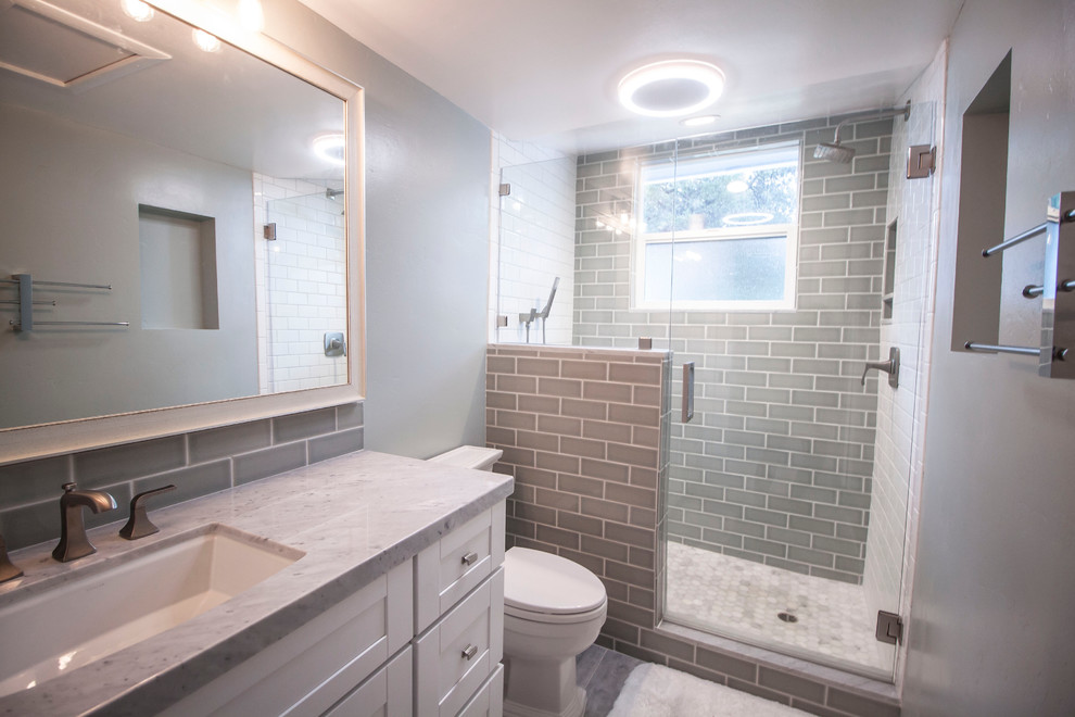 Small contemporary shower room bathroom in Los Angeles with shaker cabinets, white cabinets, an alcove shower, a one-piece toilet, blue tiles, glass tiles, blue walls, porcelain flooring, a submerged sink and marble worktops.