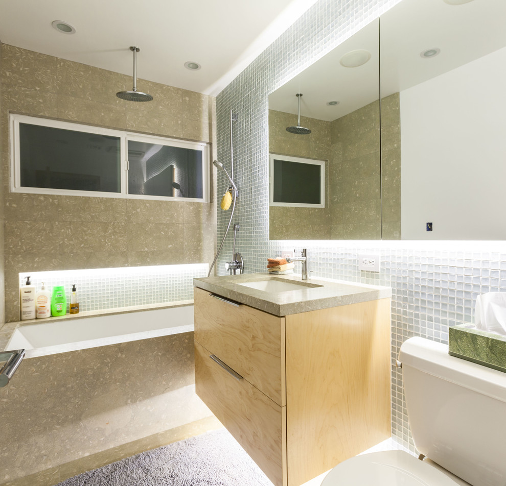 Idéer för funkis badrum, med ett undermonterad handfat, släta luckor, skåp i ljust trä, bänkskiva i kalksten, ett undermonterat badkar, en dusch/badkar-kombination och mosaik