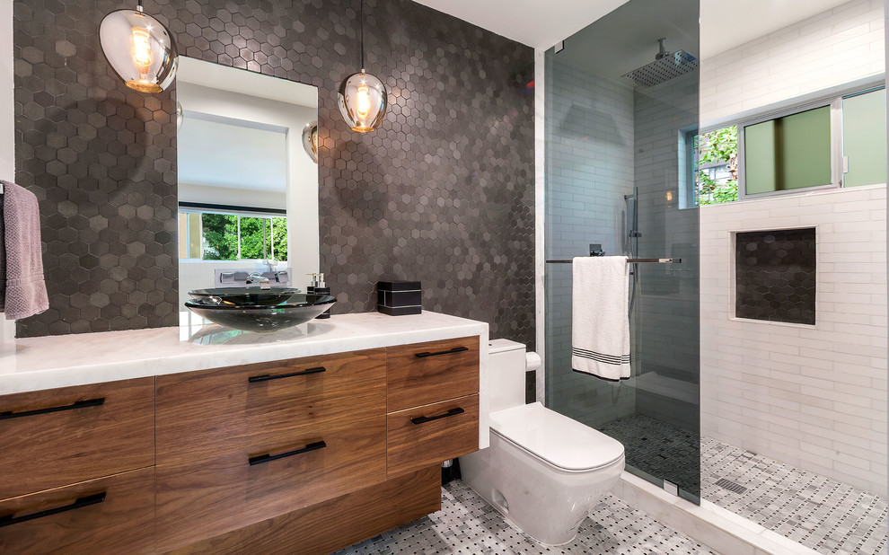 Immagine di una stanza da bagno con doccia moderna di medie dimensioni con ante lisce, ante in legno scuro, doccia aperta, WC monopezzo, pareti grigie e lavabo a bacinella