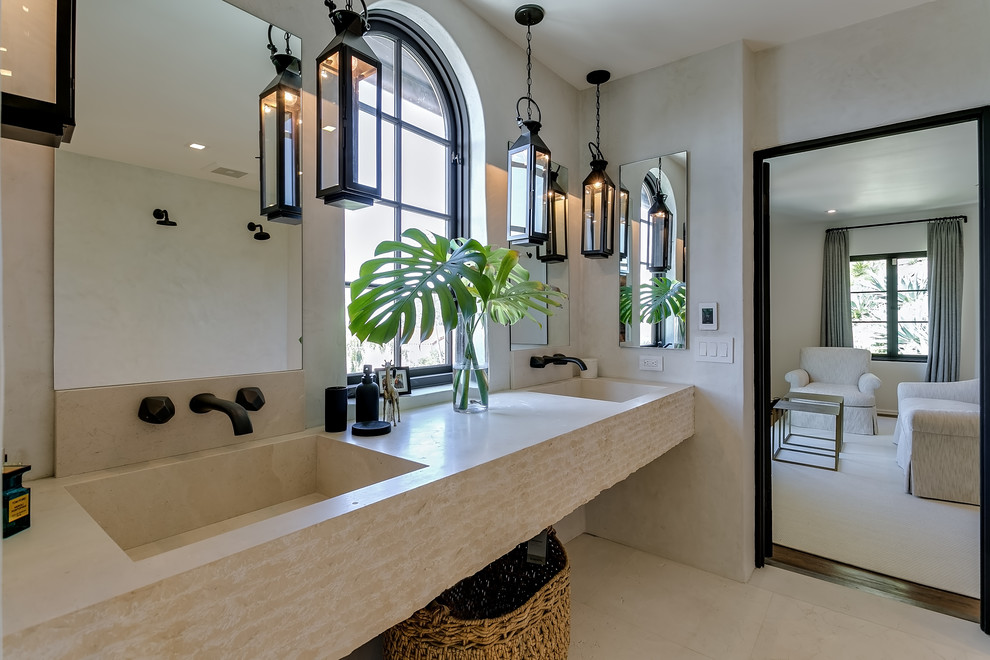 На фото: ванная комната в средиземноморском стиле с бежевой плиткой, полом из известняка, подвесной раковиной, столешницей из гранита и бежевым полом с