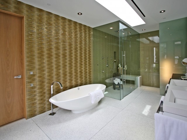 Photo of a medium sized contemporary ensuite bathroom in Los Angeles with flat-panel cabinets, white cabinets, a freestanding bath, an alcove shower, beige tiles, green tiles, glass sheet walls, multi-coloured walls, ceramic flooring, a submerged sink, solid surface worktops, white floors and a hinged door.
