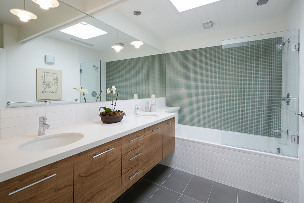 Стильный дизайн: ванная комната в стиле ретро с врезной раковиной, плоскими фасадами, фасадами цвета дерева среднего тона, ванной в нише, душем над ванной и белой плиткой - последний тренд
