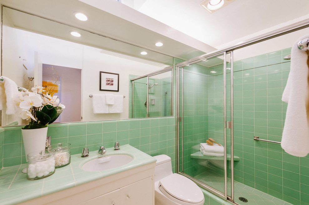 Foto di una stanza da bagno con doccia minimalista di medie dimensioni con ante lisce, ante bianche, doccia alcova, WC monopezzo, piastrelle verdi, piastrelle in ceramica, pareti verdi, lavabo sottopiano, top piastrellato e porta doccia scorrevole