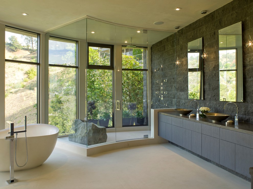 Modernes Badezimmer mit freistehender Badewanne, Aufsatzwaschbecken und Steinwänden in Los Angeles