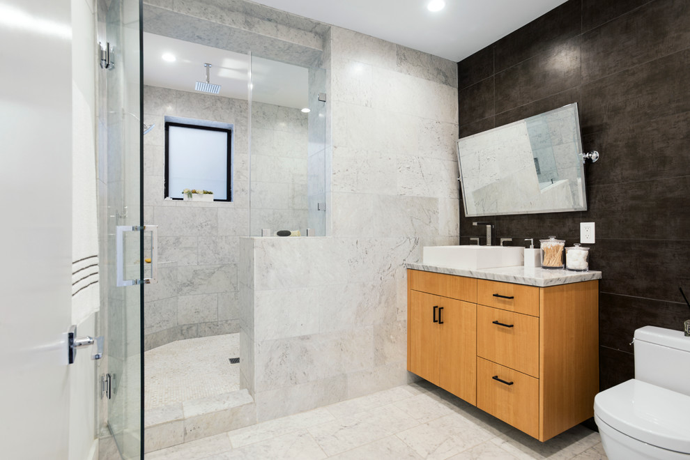 Example of a mid-sized trendy kids' marble tile marble floor and white floor bathroom design in Los Angeles with flat-panel cabinets, medium tone wood cabinets, a one-piece toilet, a vessel sink, marble countertops, a hinged shower door and multicolored countertops