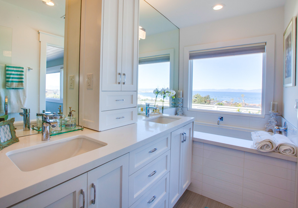 Ejemplo de cuarto de baño principal costero grande con puertas de armario blancas y baldosas y/o azulejos blancos
