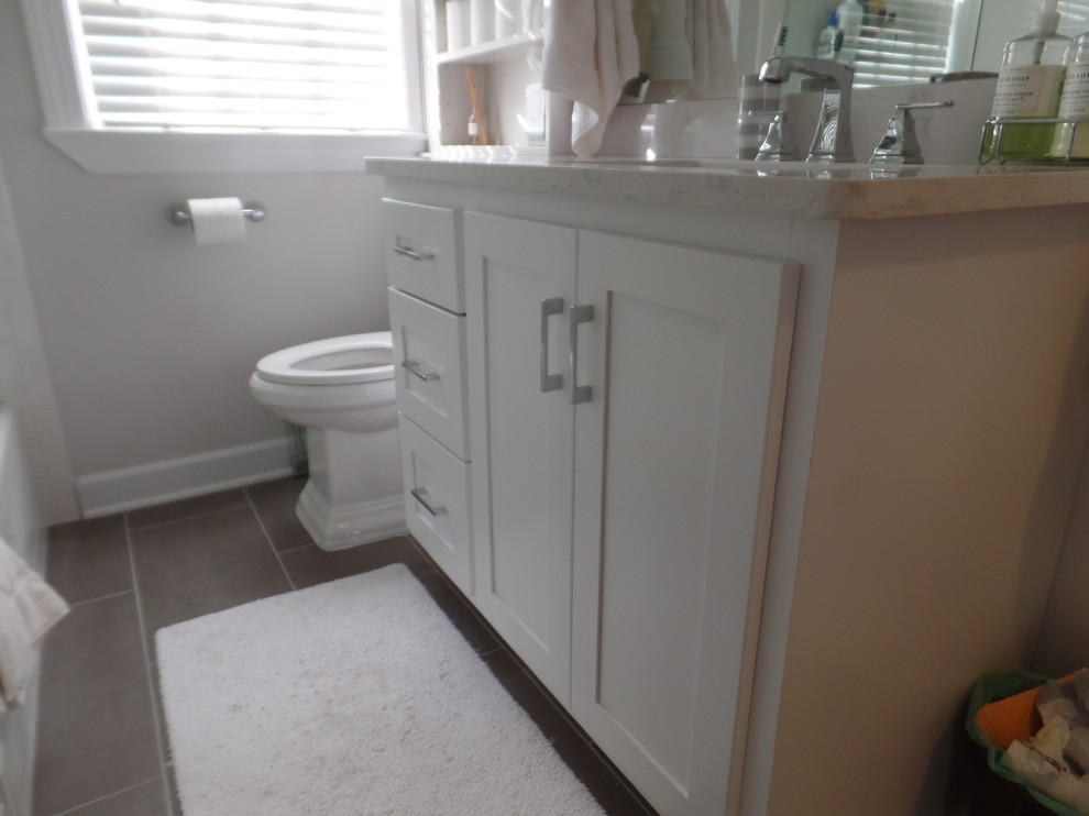 Photo of a small classic family bathroom in Other with shaker cabinets, white cabinets, an alcove bath, an alcove shower, a two-piece toilet, grey tiles, ceramic tiles, grey walls, porcelain flooring, a submerged sink and engineered stone worktops.