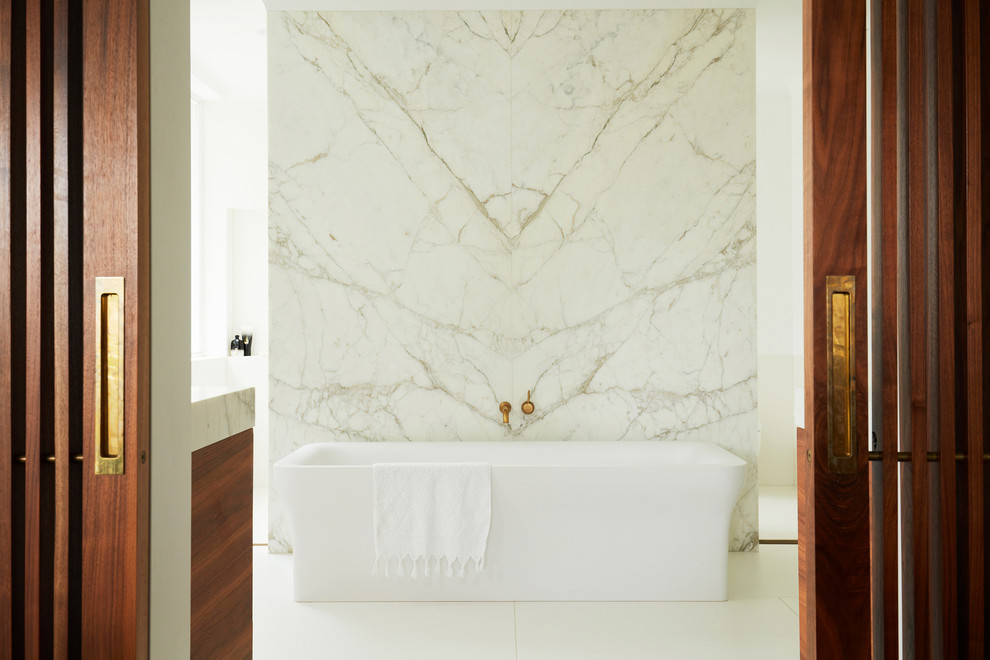 Foto på ett funkis badrum, med ett fristående badkar, vit kakel, vita väggar och vitt golv