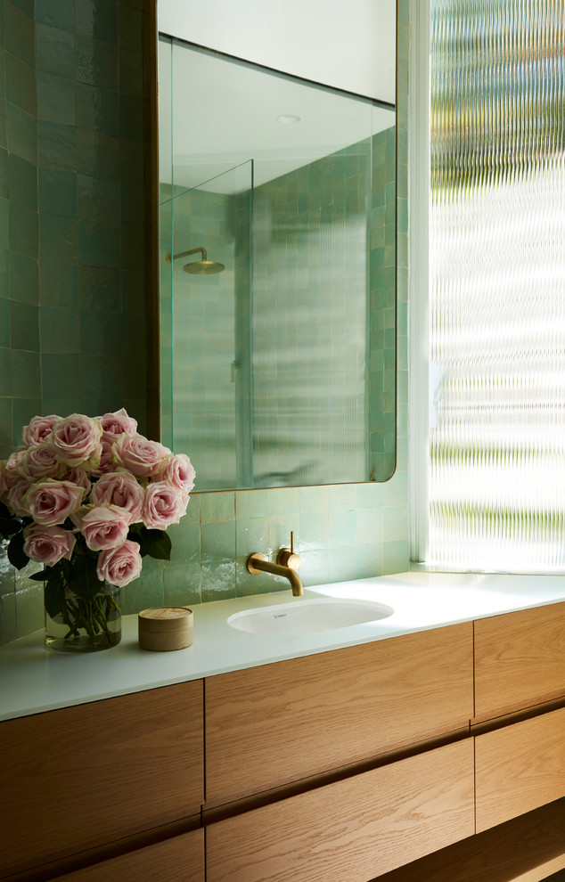 Источник вдохновения для домашнего уюта: ванная комната в стиле модернизм с плоскими фасадами, фасадами цвета дерева среднего тона, зеленой плиткой, зелеными стенами, монолитной раковиной и белой столешницей