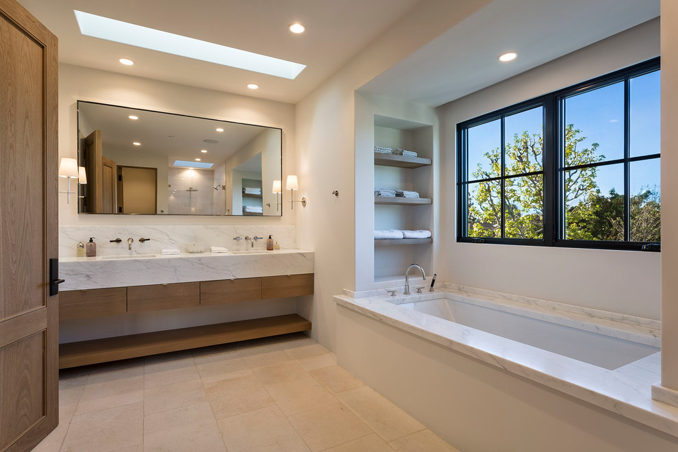 Trendy master beige floor bathroom photo in Boise with flat-panel cabinets, medium tone wood cabinets, an undermount tub and white walls