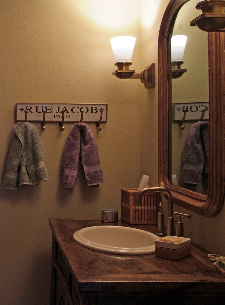 Esempio di una stanza da bagno stile rurale con lavabo da incasso, consolle stile comò, ante con finitura invecchiata e top in legno