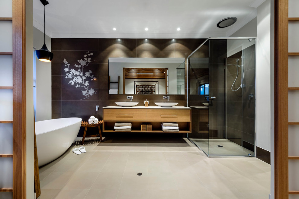 Пример оригинального дизайна: большая главная ванная комната в восточном стиле с настольной раковиной, плоскими фасадами, фасадами цвета дерева среднего тона, отдельно стоящей ванной, угловым душем и черной плиткой
