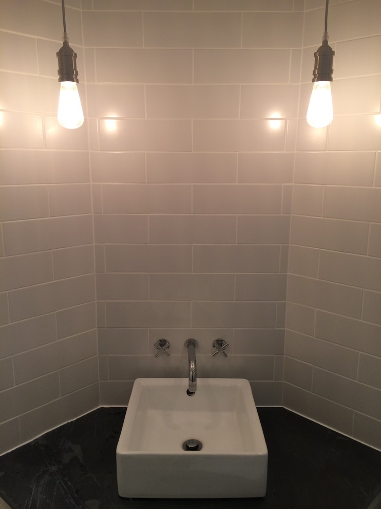 Aménagement d'une salle de bain principale industrielle avec une vasque, un plan de toilette en surface solide, une douche ouverte, un carrelage gris, des dalles de pierre, un mur blanc et sol en béton ciré.