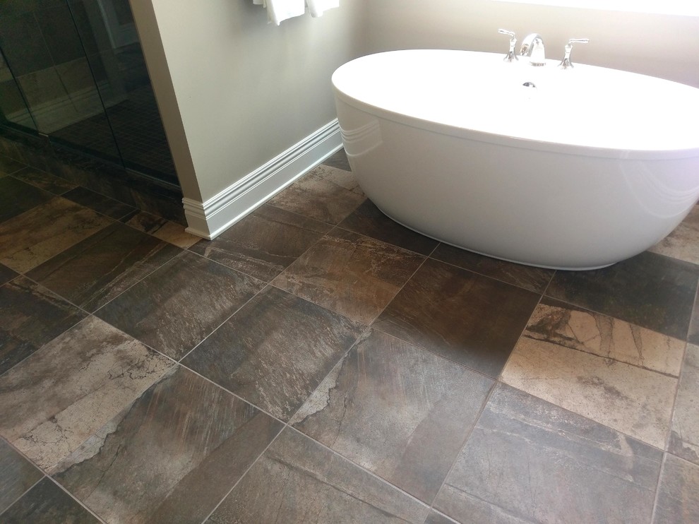 Inspiration for a large timeless master brown tile and porcelain tile porcelain tile and brown floor bathroom remodel in Cleveland with raised-panel cabinets, black cabinets, brown walls, an undermount sink, granite countertops and a hinged shower door
