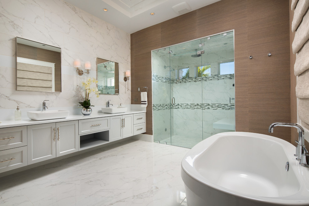 Large traditional ensuite bathroom in Miami with recessed-panel cabinets, white cabinets, a freestanding bath, an alcove shower, brown walls, a vessel sink, marble flooring and a hinged door.