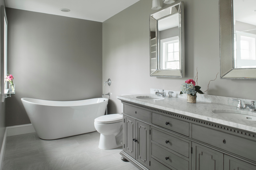 Пример оригинального дизайна: главная ванная комната среднего размера в современном стиле с мраморной столешницей, отдельно стоящей ванной, серыми стенами, фасадами с утопленной филенкой и серыми фасадами