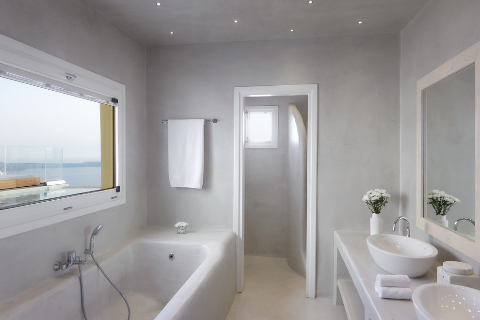 This is an example of a mediterranean ensuite bathroom in London with open cabinets, yellow cabinets, a built-in bath, white walls, white floors and white worktops.