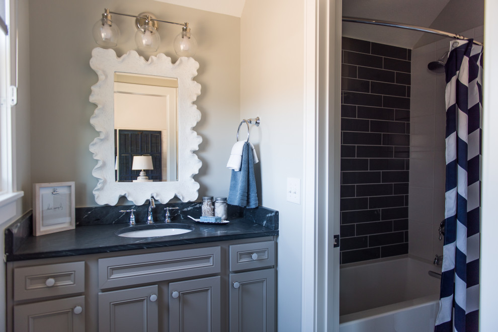 Immagine di una stanza da bagno padronale minimal di medie dimensioni con ante in stile shaker, ante grigie, vasca da incasso, doccia ad angolo, pareti beige, lavabo sottopiano, top in granito, doccia con tenda e top nero