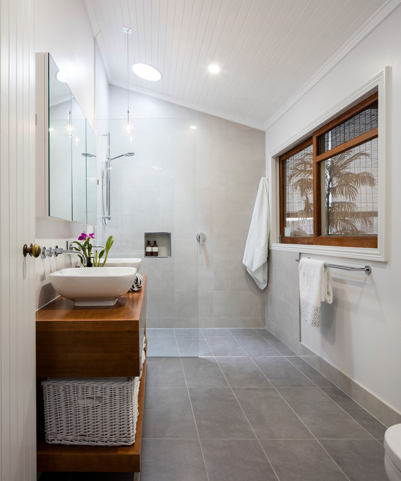 Cette image montre une salle de bain principale minimaliste en bois brun de taille moyenne avec un placard sans porte, une douche ouverte, un carrelage gris, des carreaux de porcelaine, un mur blanc, un sol en carrelage de porcelaine, un plan de toilette en bois, un sol gris et aucune cabine.