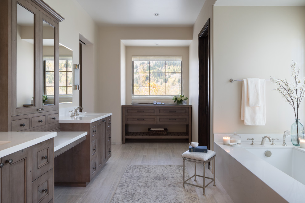На фото: главная ванная комната в стиле рустика с фасадами с утопленной филенкой, коричневыми фасадами, полновстраиваемой ванной, белой столешницей, белыми стенами и серым полом с