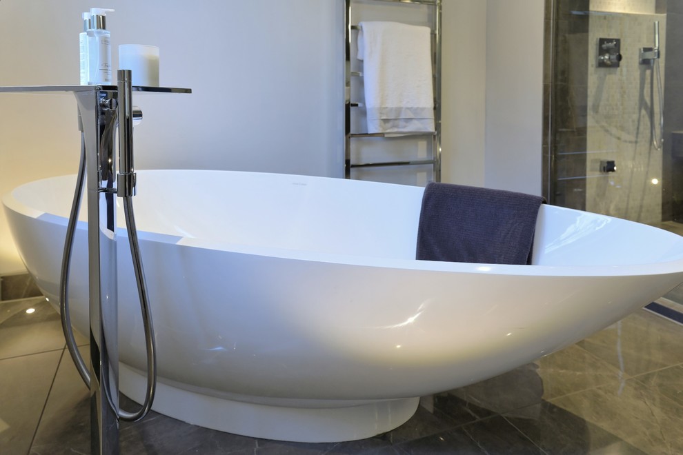 Idée de décoration pour une salle de bain principale design de taille moyenne avec une baignoire indépendante, une douche à l'italienne, un carrelage gris, des carreaux de porcelaine, un mur blanc et un sol en carrelage de porcelaine.