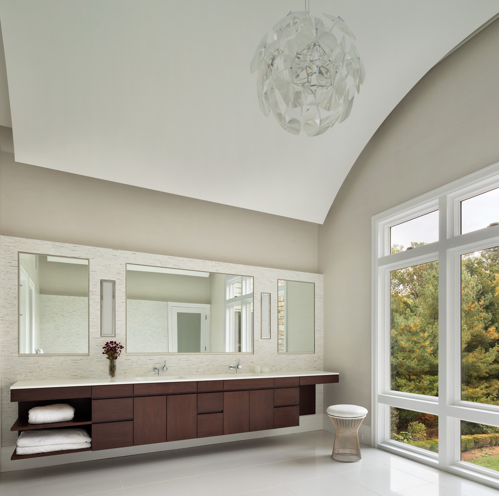 Exemple d'une salle de bain moderne en bois foncé avec un placard à porte plane, des carreaux de porcelaine, un mur beige, un sol en carrelage de porcelaine, un plan de toilette en surface solide, un carrelage beige et un lavabo intégré.