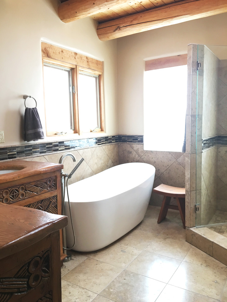 Immagine di una stanza da bagno american style di medie dimensioni con vasca freestanding, WC monopezzo, piastrelle beige, lastra di vetro, pareti beige, pavimento in gres porcellanato e top in legno