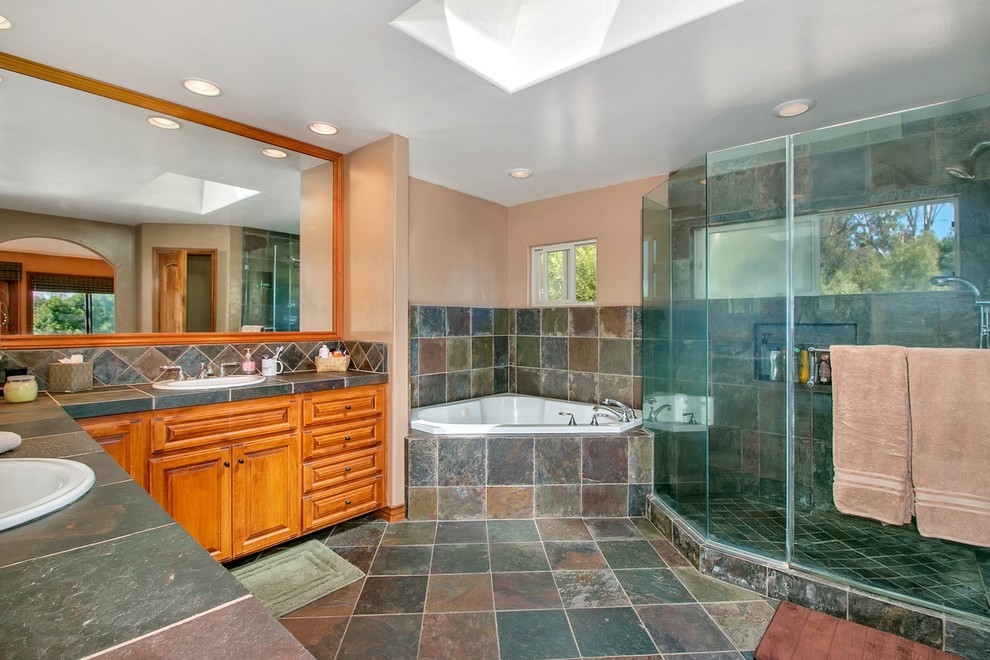 Large southwest master slate tile slate floor and multicolored floor bathroom photo in San Diego with raised-panel cabinets, medium tone wood cabinets, beige walls, a drop-in sink, a hinged shower door and gray countertops