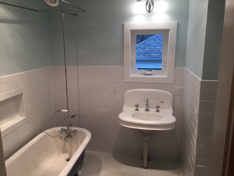Klassisk inredning av ett litet badrum, med ett badkar med tassar, en dusch/badkar-kombination, vit kakel, tunnelbanekakel, blå väggar, klinkergolv i keramik och ett piedestal handfat