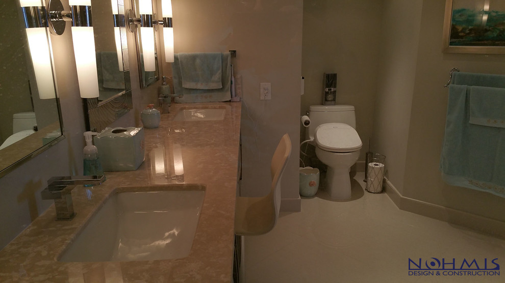 This is an example of a medium sized contemporary ensuite bathroom in Miami with raised-panel cabinets, dark wood cabinets, a freestanding bath, a shower/bath combination, a two-piece toilet, beige tiles, porcelain tiles, beige walls, porcelain flooring, an integrated sink and granite worktops.