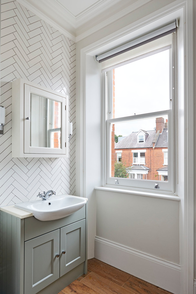 Klassisches Badezimmer mit Schrankfronten mit vertiefter Füllung, grünen Schränken, weißen Fliesen, beiger Wandfarbe, Einbauwaschbecken, braunem Boden und beiger Waschtischplatte in London