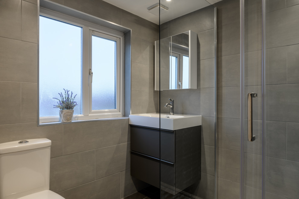 Modernes Duschbad mit offener Dusche, Toilette mit Aufsatzspülkasten, grauen Fliesen, grauer Wandfarbe, Keramikboden, Wandwaschbecken, grauem Boden und Schiebetür-Duschabtrennung in London