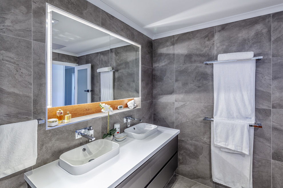 ブリスベンにあるコンテンポラリースタイルのおしゃれな浴室 (フラットパネル扉のキャビネット、グレーのキャビネット、グレーのタイル、グレーの壁、オーバーカウンターシンク、グレーの床、白い洗面カウンター) の写真