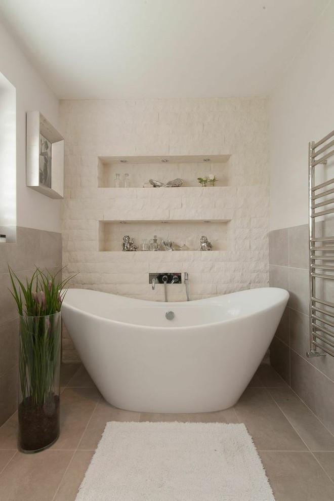 Inredning av ett modernt en-suite badrum, med ett fristående badkar, grå kakel och vita väggar