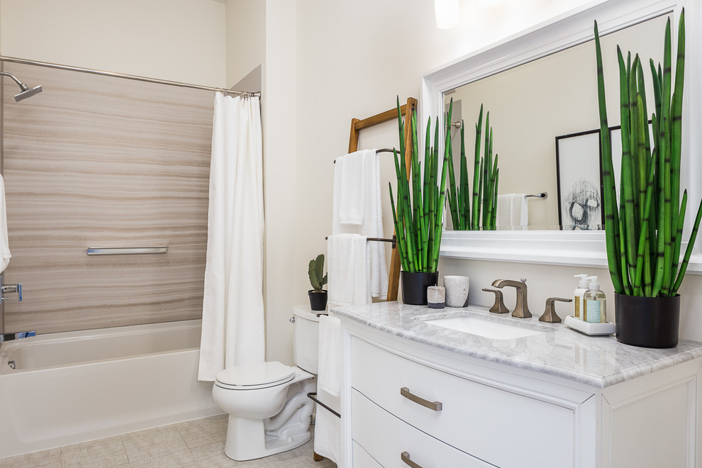 Стильный дизайн: ванная комната среднего размера в стиле неоклассика (современная классика) с фасадами островного типа, белыми фасадами, ванной в нише, душем над ванной, унитазом-моноблоком, серой плиткой, плиткой из листового камня, белыми стенами, полом из керамической плитки, врезной раковиной, мраморной столешницей, серым полом и шторкой для ванной - последний тренд