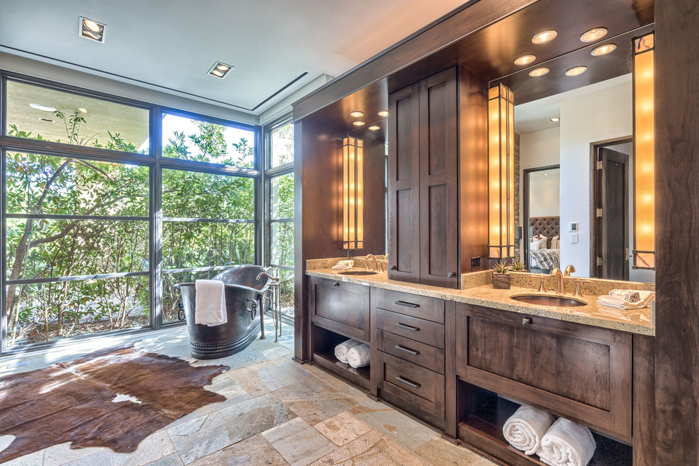 На фото: главная ванная комната в средиземноморском стиле с фасадами в стиле шейкер, темными деревянными фасадами, отдельно стоящей ванной, врезной раковиной и бежевым полом