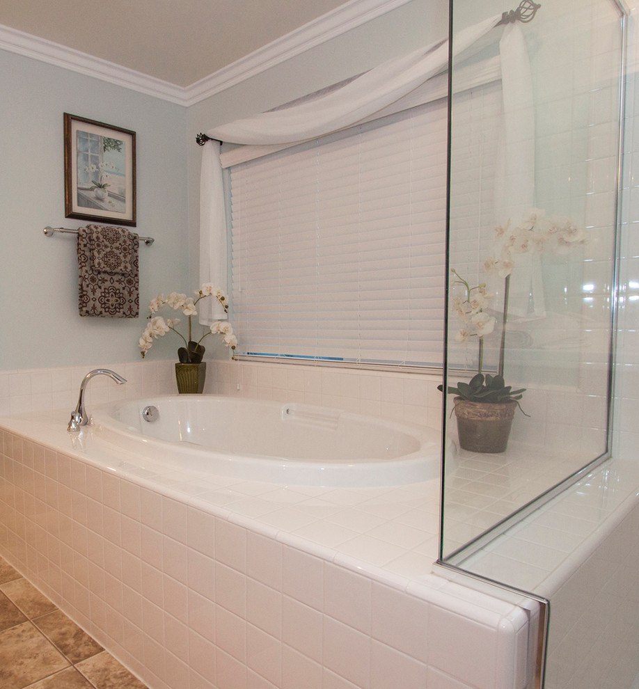 Foto på ett funkis badrum, med ett platsbyggt badkar, vit kakel, keramikplattor, blå väggar och travertin golv